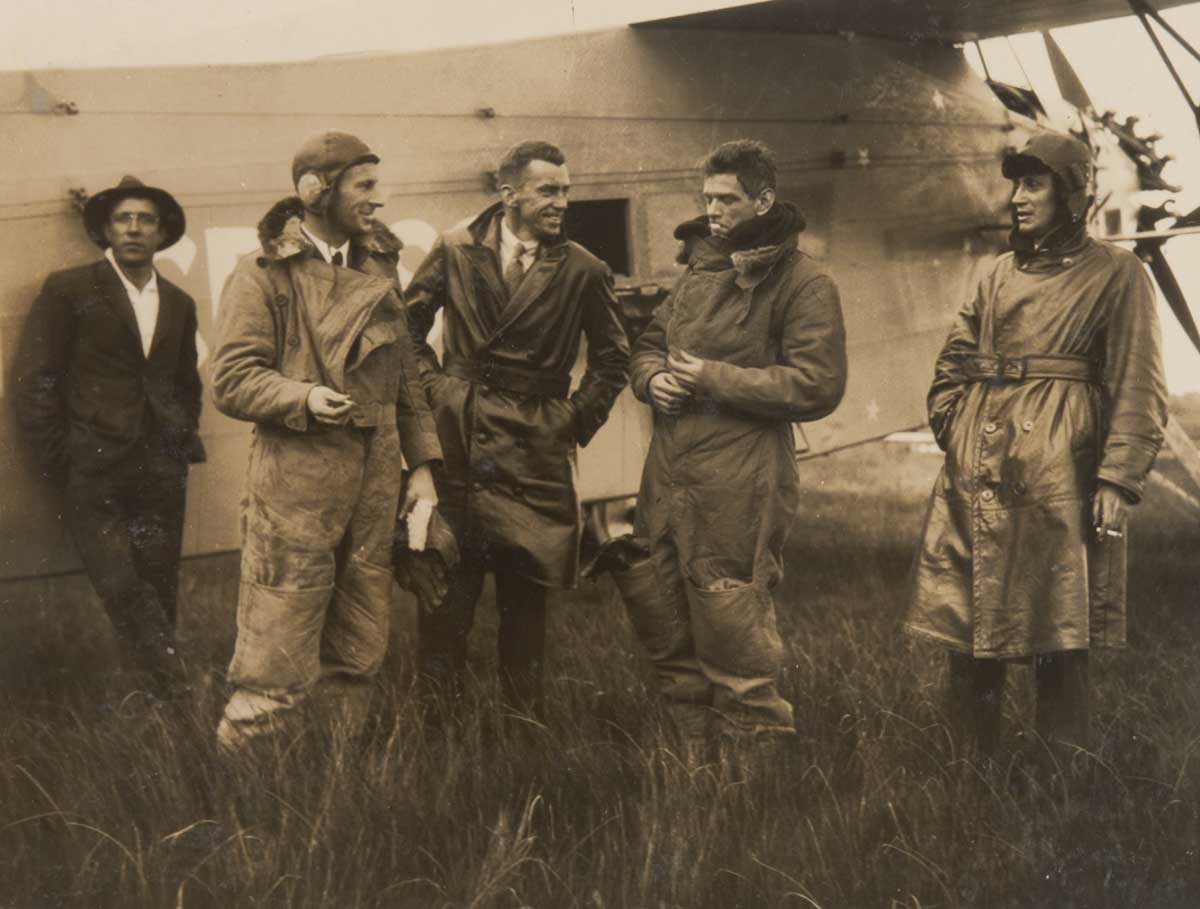 Black and white photo of five men in front of an aircraft. - click to view larger image