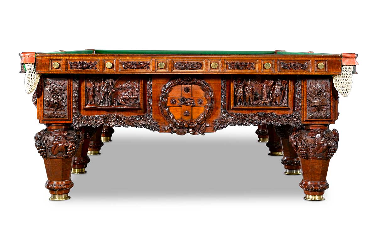 View of a billiard table with ornate carved designs to sides and legs. - click to view larger image