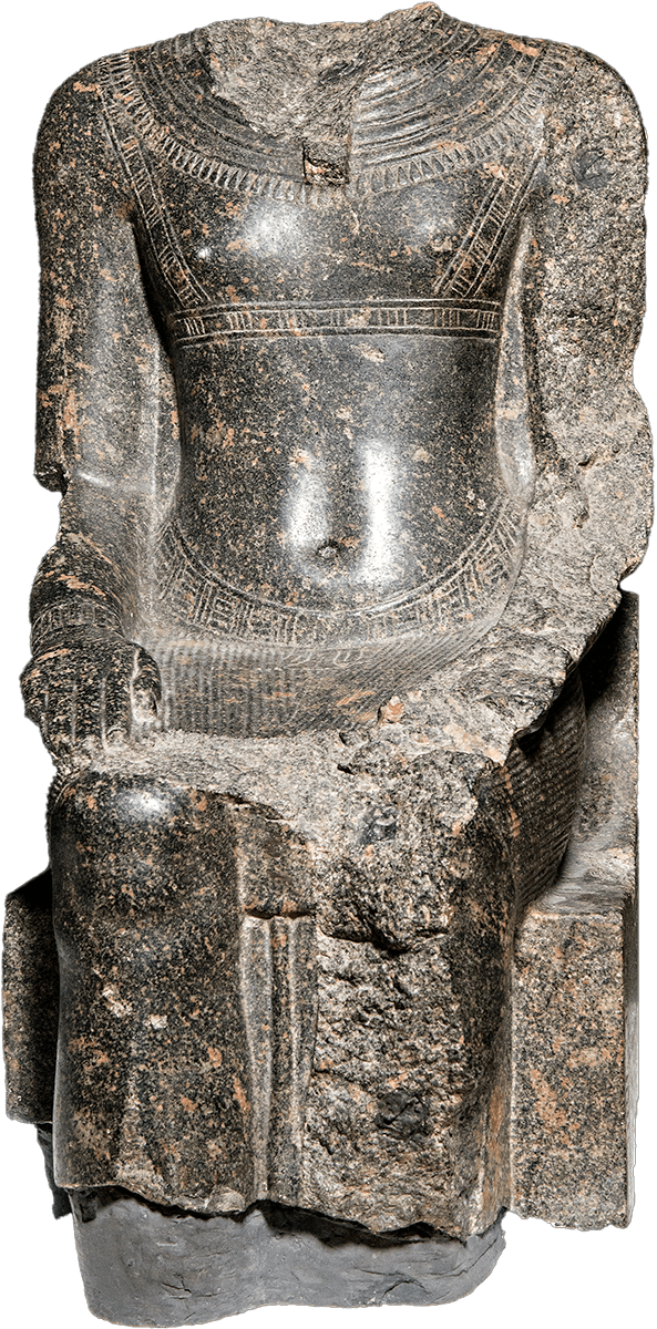 A stone carved statue of a seated figure, missing its head and most of one arm and leg.