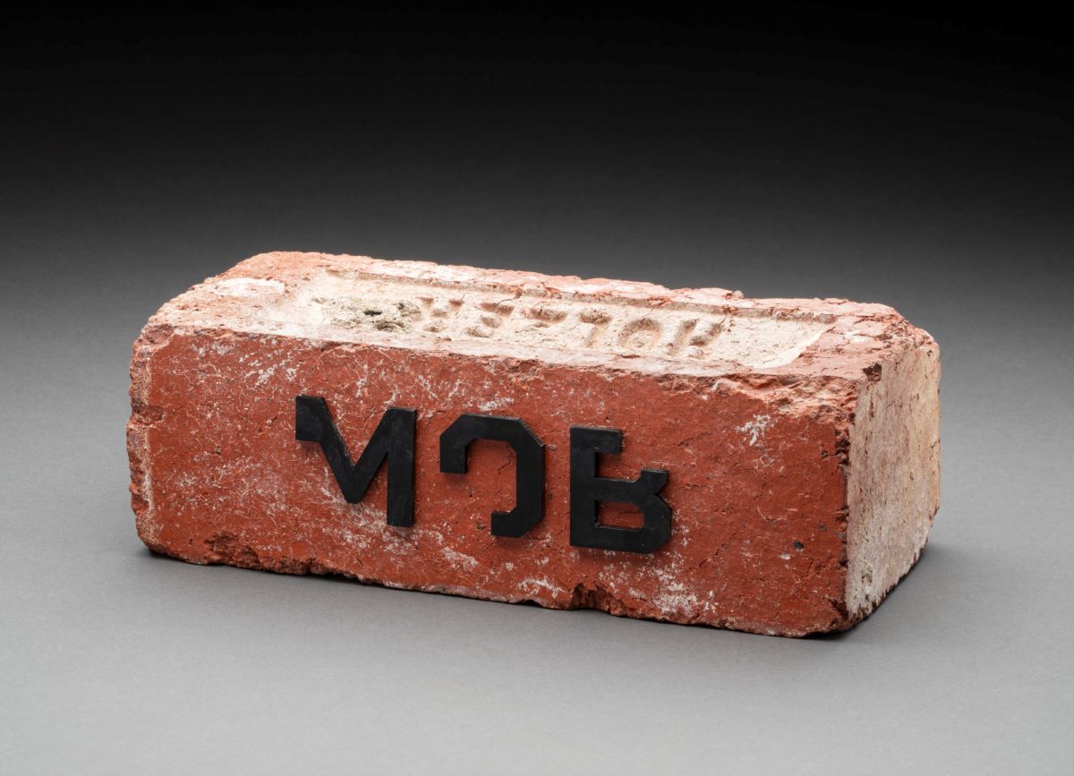 Photo of a red brick with the letters M, O, B on it in black - click to view larger image