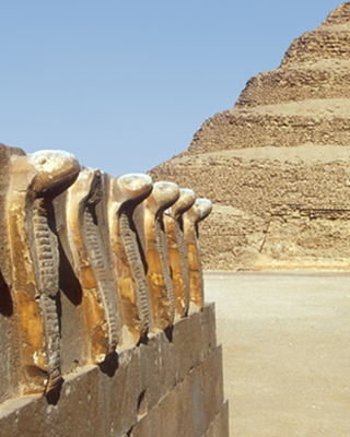 Statues outside a pyramid in a desert landscape.