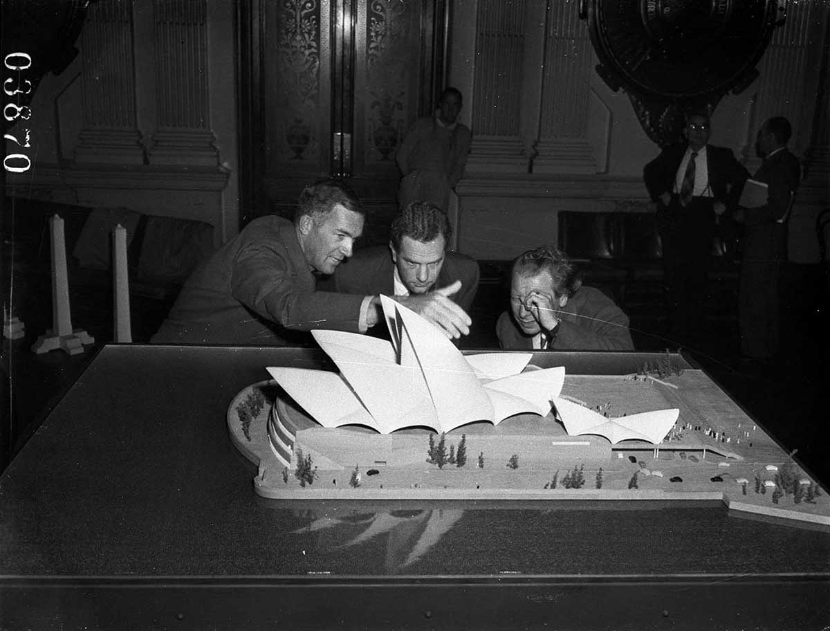 Utzon and two other men scrutinising a model of the Opera House.
