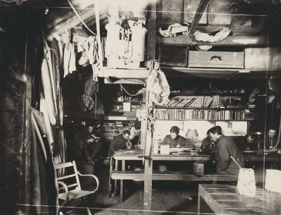 black and white photo of men inside hut
