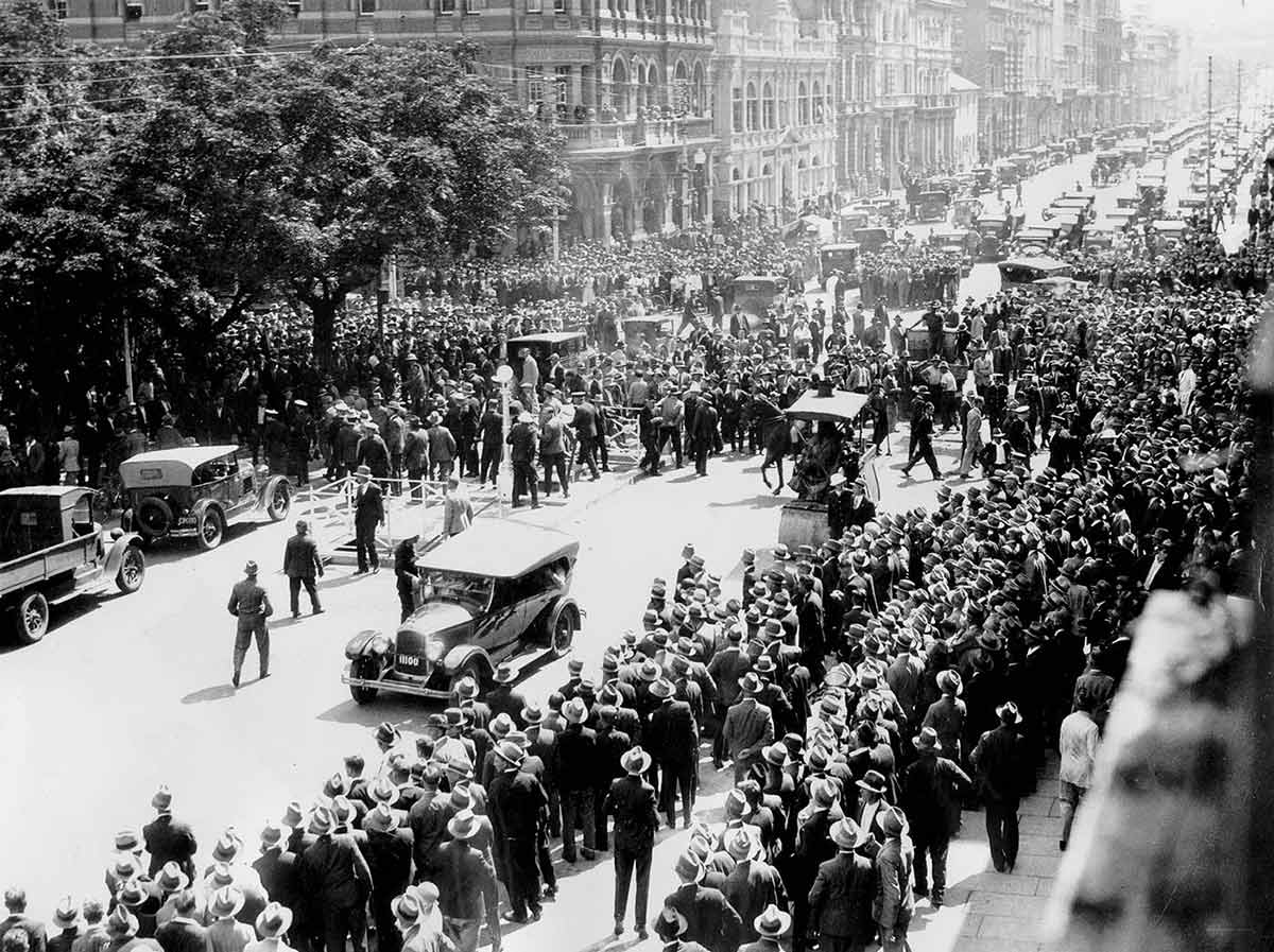 Photo taken from a second-storey window showing hundreds of men proceeding down a main street.