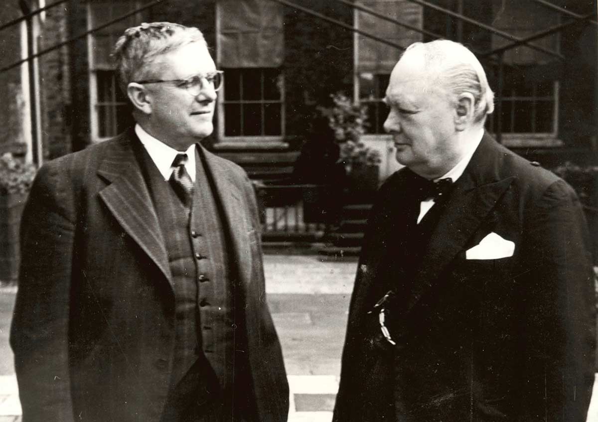 Evatt and Churchill stand next to each other looking at each other.