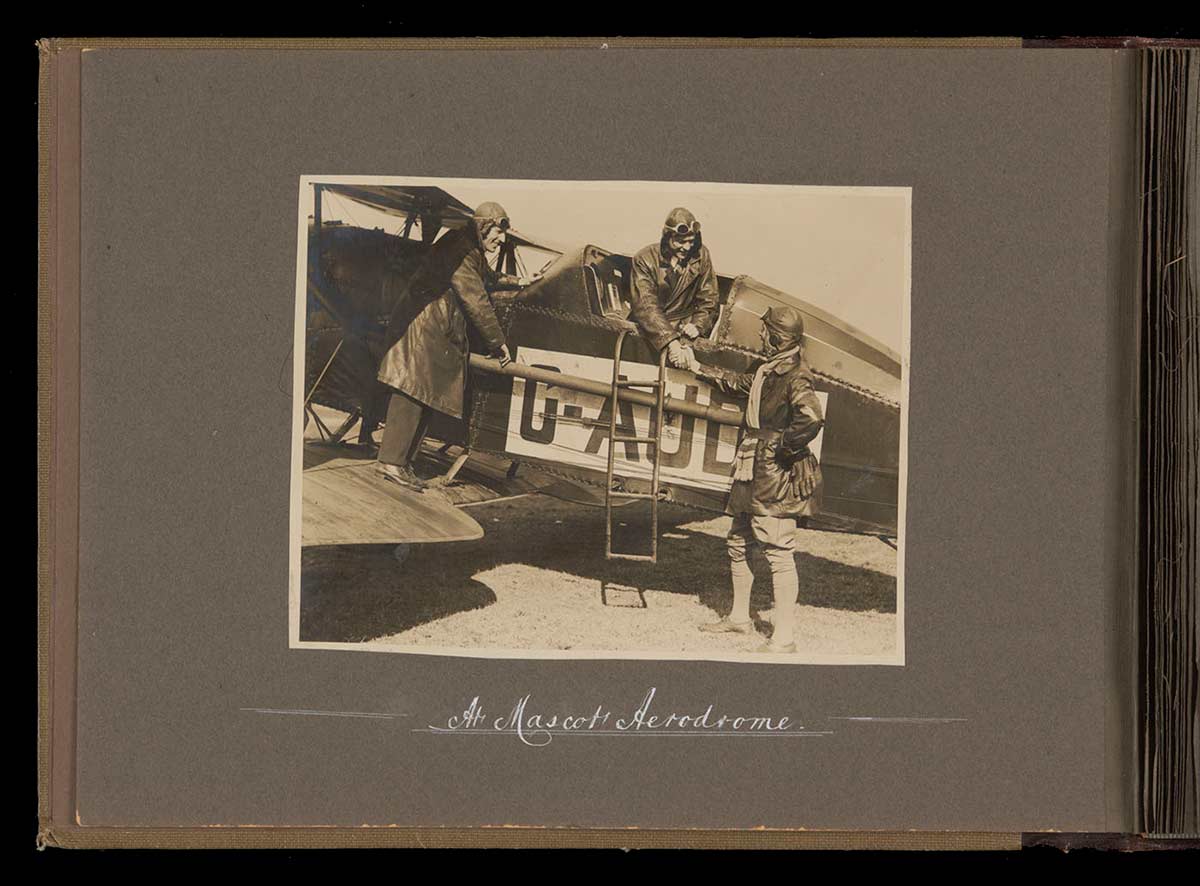 Black and white photo of Kingsford Smith, Ulm and a third man with the aviators' biplane. - click to view larger image