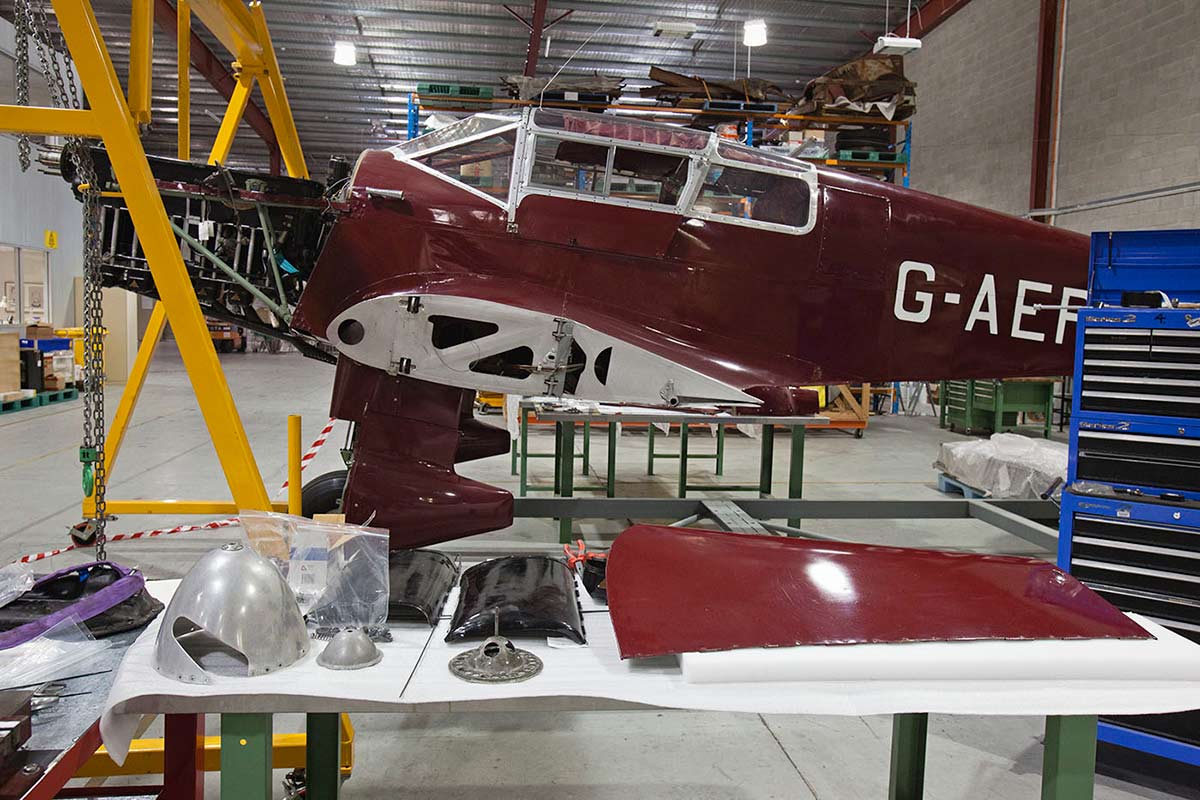 Maroon and silver Percival Type D3 Gull Six three seat cabin monoplane under maintenance in the workshop. - click to view larger image
