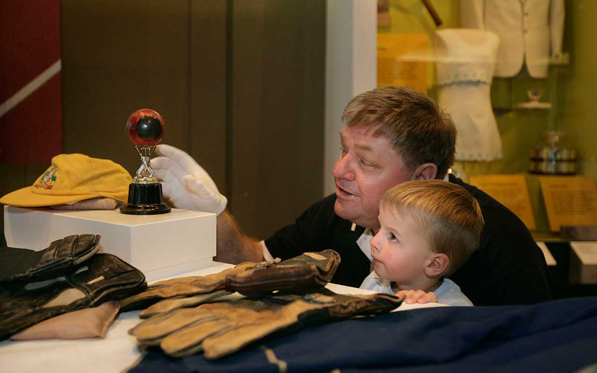 Swan Richards shows a young Museum visitor Wally Grout's record-breaking ball and other cricket gear including a cap and gloves.