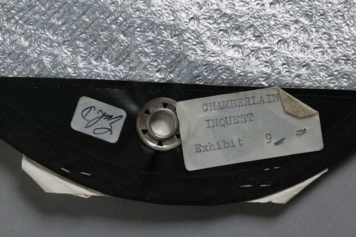 Part of a silver space blanket with a sticker reading 'Chamberlain inquest, exhibit 9'. - click to view larger image