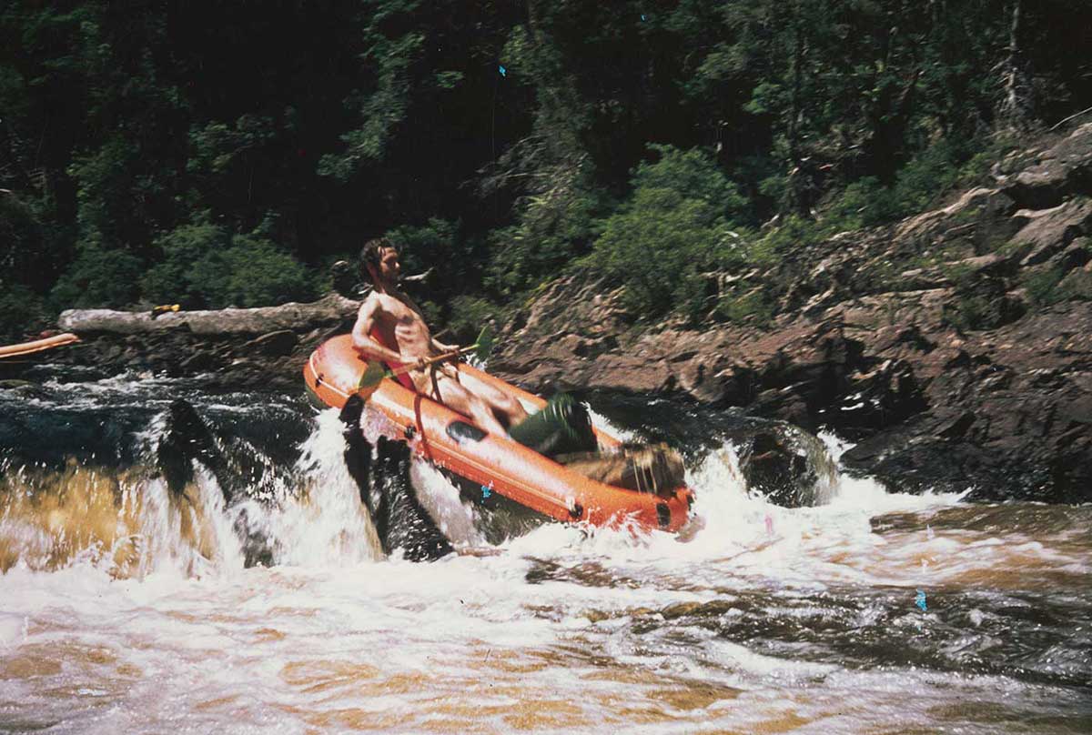 A man in a raft leans back as he negotiates the rapids in a river. - click to view larger image
