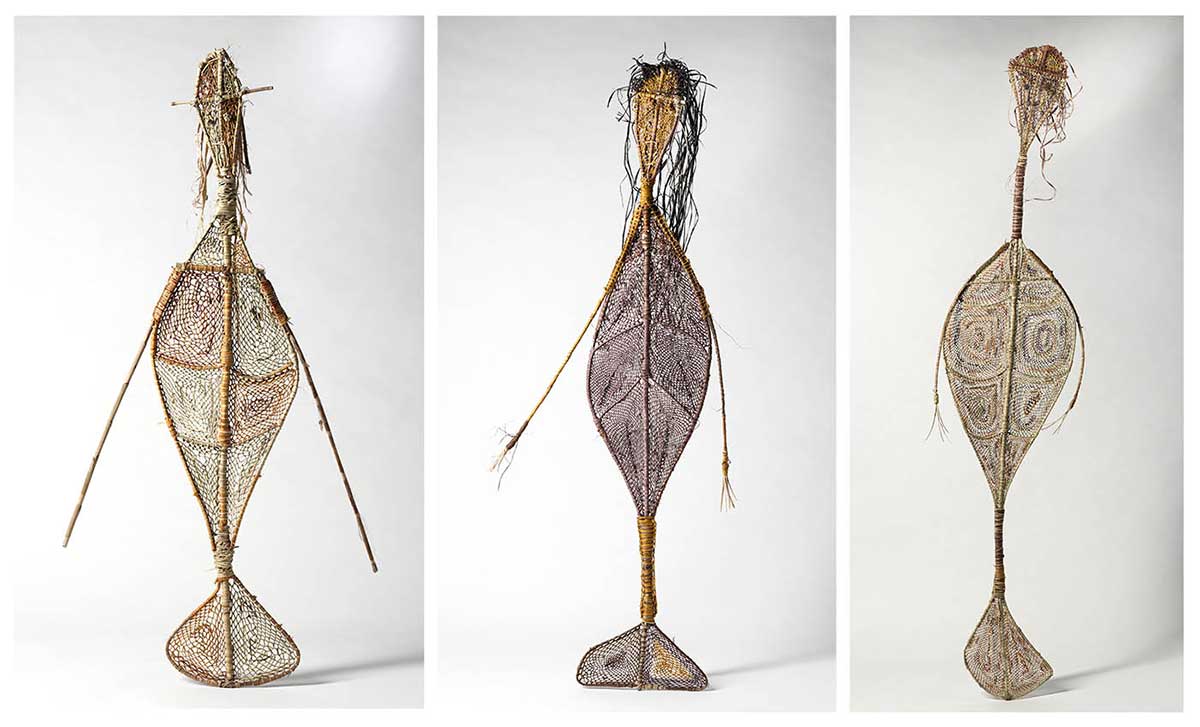 Three woven grass, mermaid-like yawkyawk sculptures with arms, tails and trailing hair.