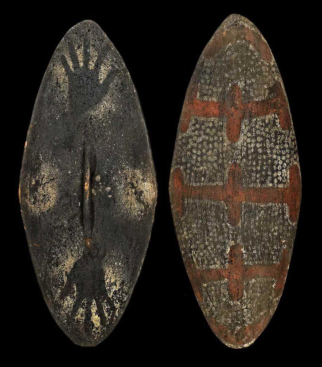 Front view and back view of an ellipse-shaped wooden shield; featuring a red and white ochre design on the front hand markings on the back. - click to view larger image