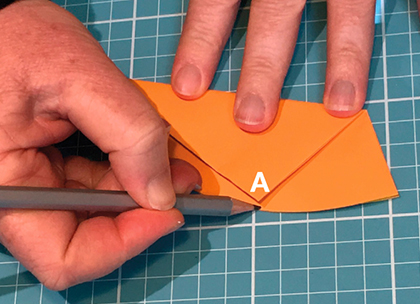A large orange star cut out from orange paper. Two fingers point to two points on each side of the star.