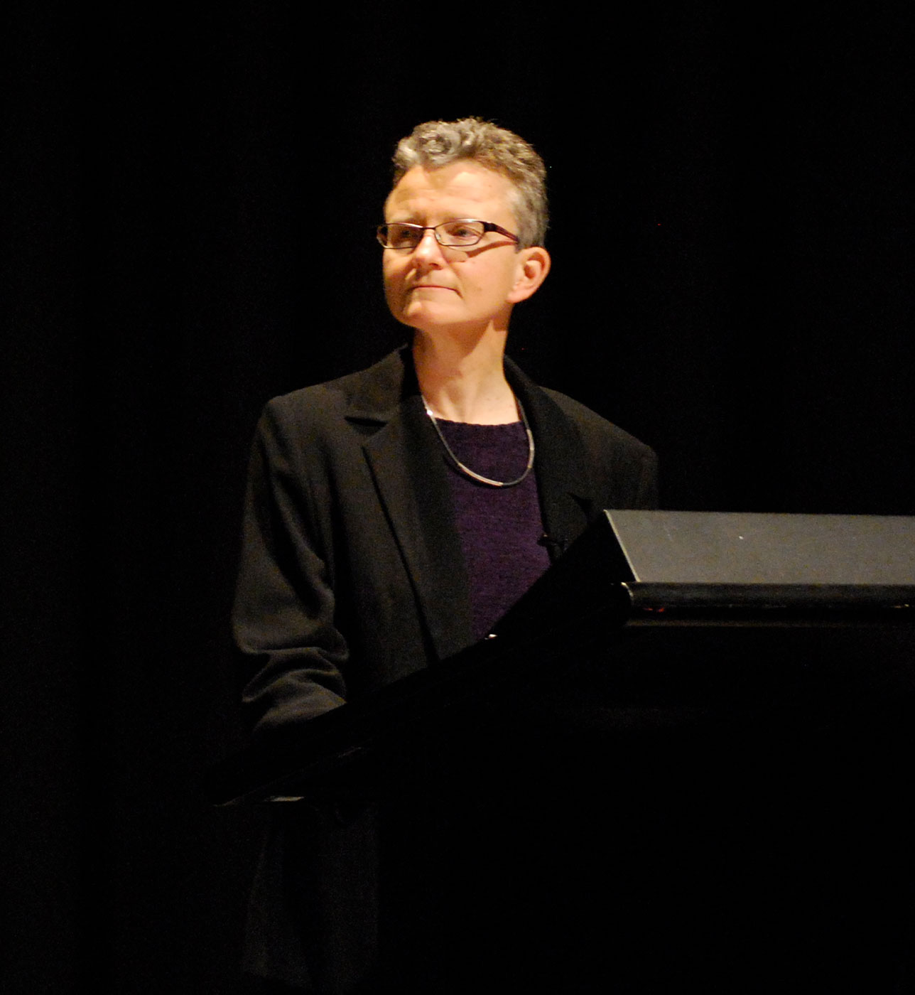 A woman stands at a lectern on a stage. - click to view larger image
