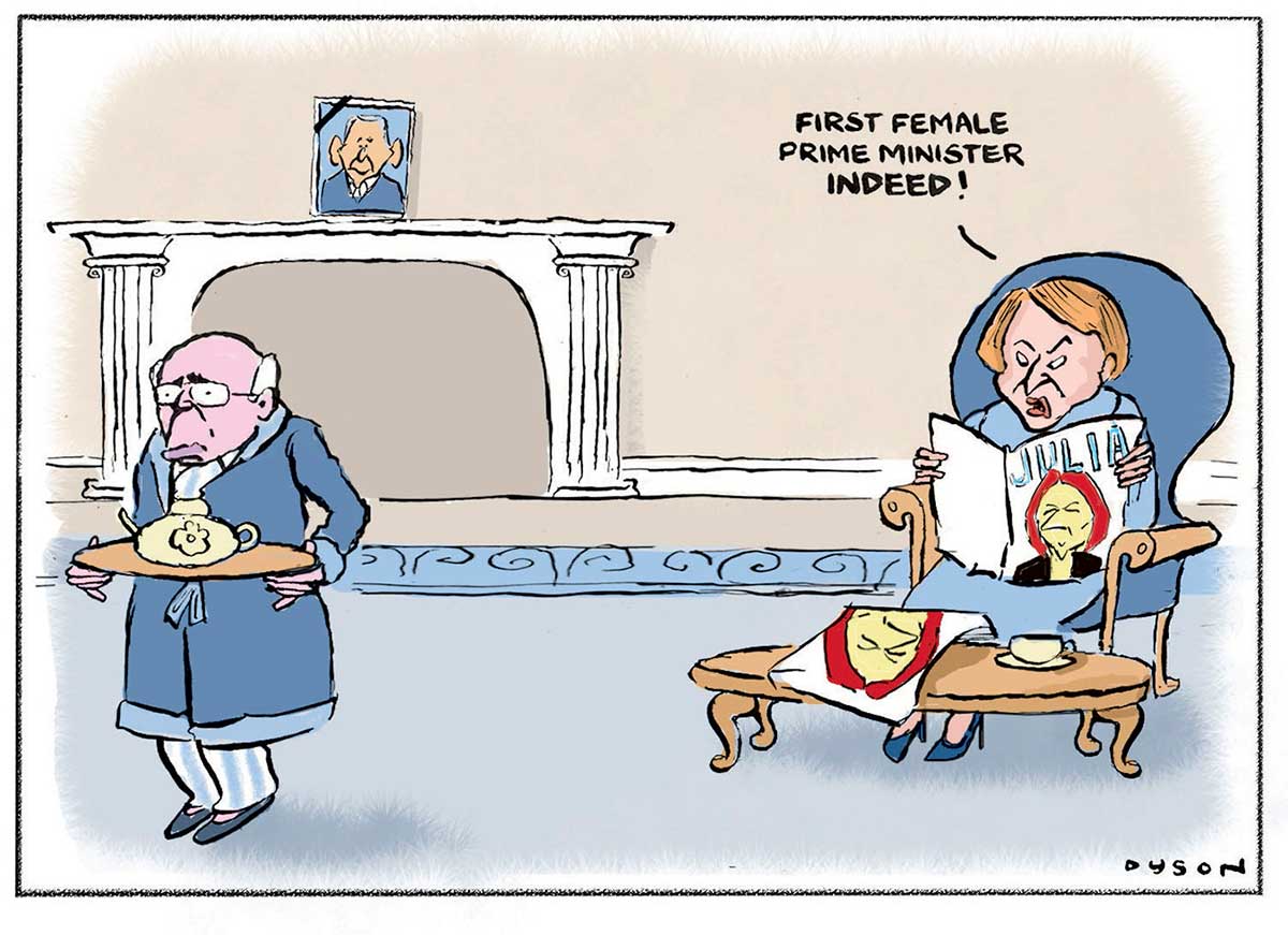 Political cartoon depicting John and Janette Howard at home. He is at the left of the cartoon, wearing pyjamas and a dressing gown and carrying a platter with a teapot on it. He has a downtrodden expression on his face. She is sitting at the right of the cartoon in a large blue chair reading a magazine with an image of Julia Gillard on the front. She has a look of annoyance on her face and is saying 'First female prime minister indeed!' In the background is a fireplace with a picture of George W Bush above it. - click to view larger image