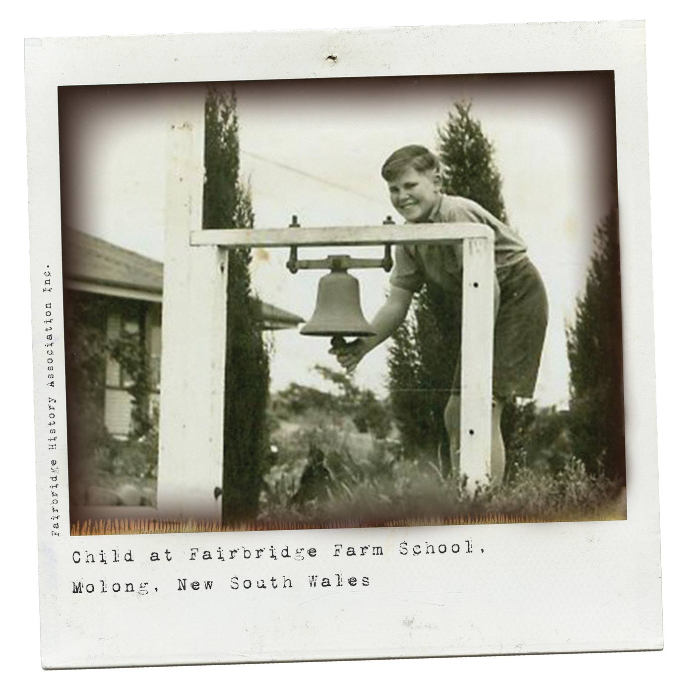 A black and white Polaroid photograph of a young boy who is smiling at the camera as he stands holding the clapper of a large bell which is attached to a wooden post. Typewritten text underneath reads: 'Child at Fairbridge Farm School. Molong. New South Wales'. Smaller text, on the left-hand side of the image, in a vertical direction, reads 'Fairbridge History Association Inc.'. - click to view larger image