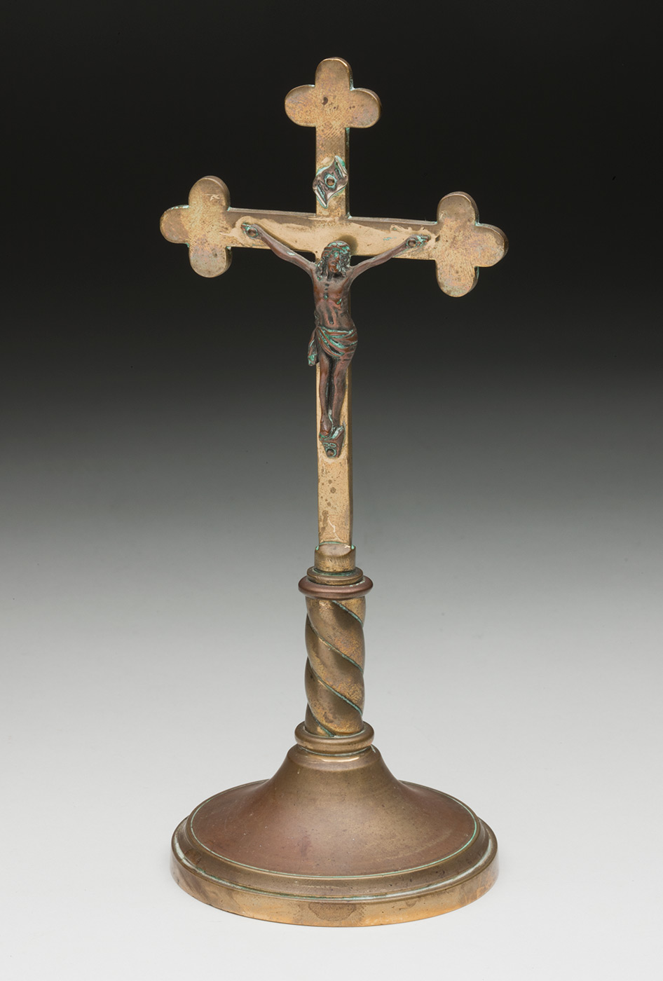 A copper cross and figure of Jesus mounted on a round stand. - click to view larger image