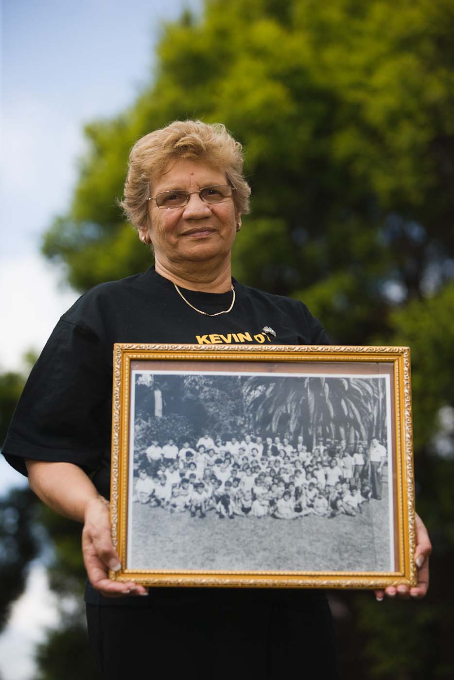 Mary Terszak holding a photograph of herself with her school mates. - click to view larger image
