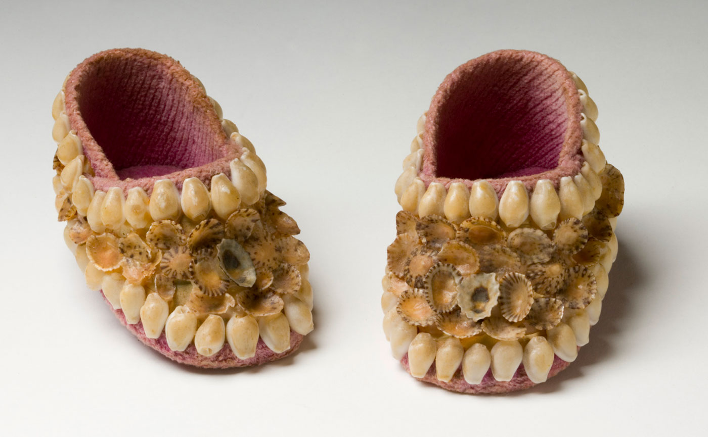 Small pink baby shoes decorated with yellow-brown shells. - click to view larger image