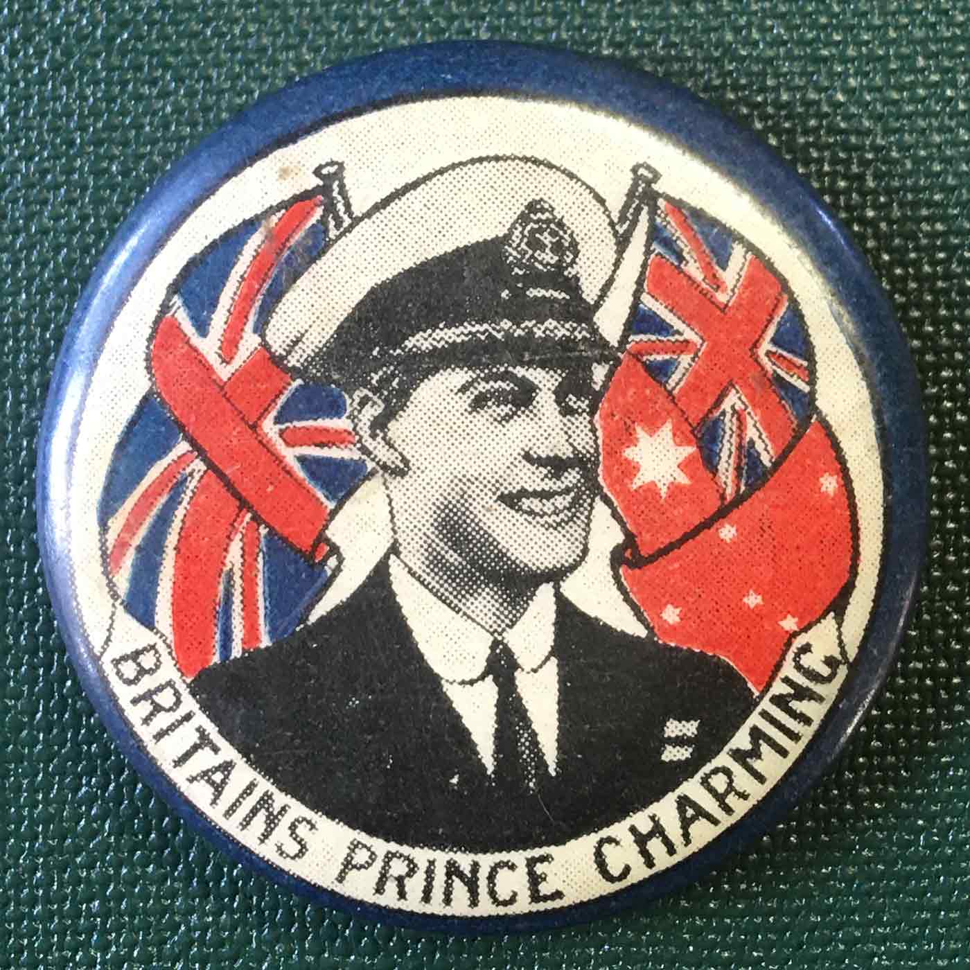 Colour photograph of a badge with an illustration of Prince Edward smiling in front of the British flag. There is a label with the text: BRITAIN'S PRINCE CHARMING. - click to view larger image