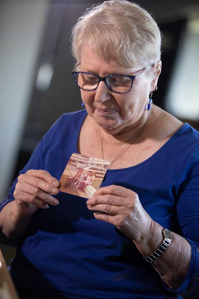 A woman holds a photograph of family members. - click to view larger image