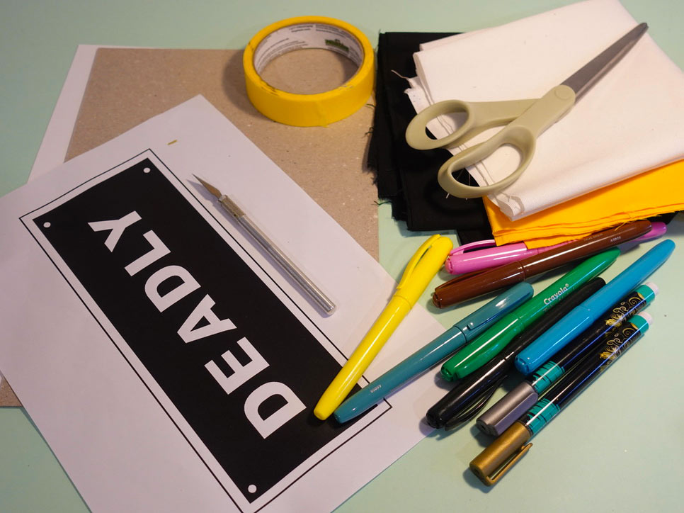 Craft activity featuring a range of materials including tape, scissors, paper, colouring pens and a stencil of the word 'DEADLY'.