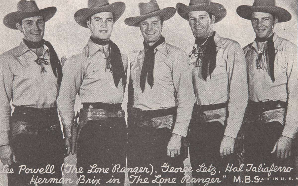 A postcard featuring a black and white photograph of five men dressed as cowboys with hats, handkerchiefs around their necks and gun holsters around their hips. Printed text at the bottom of the image reads 