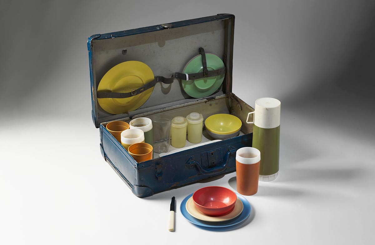 A picnic set, consisting of a dark blue cardboard suitcase, including plastic dinner plates, plastic side plates, plastic bowls, plastic beverage cups, a salt and pepper shaker set, a thermos and cutlery. - click to view larger image