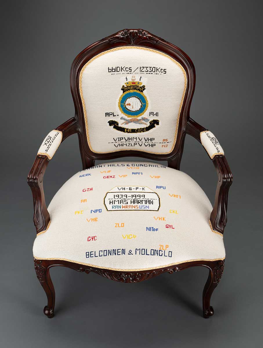 A chair with embroidered design including the Harman naval base coat of arms and text 'WRANS' and 'Belconnen and Molonglo'.