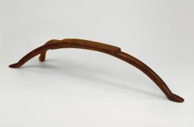 Headrest made of a hard wood and used as a pillow. A semi-circular piece with a flat, rectangular upper surface. One side forms one leg and the other divides into two legs.