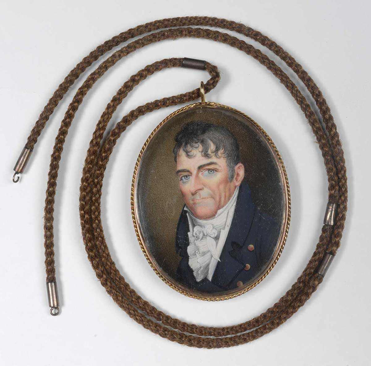 miniature portrait with necklace attached. The portrait depicts a man wearing a blue coat and a flouncy cravat. He has blue eyes and black wavy hair.