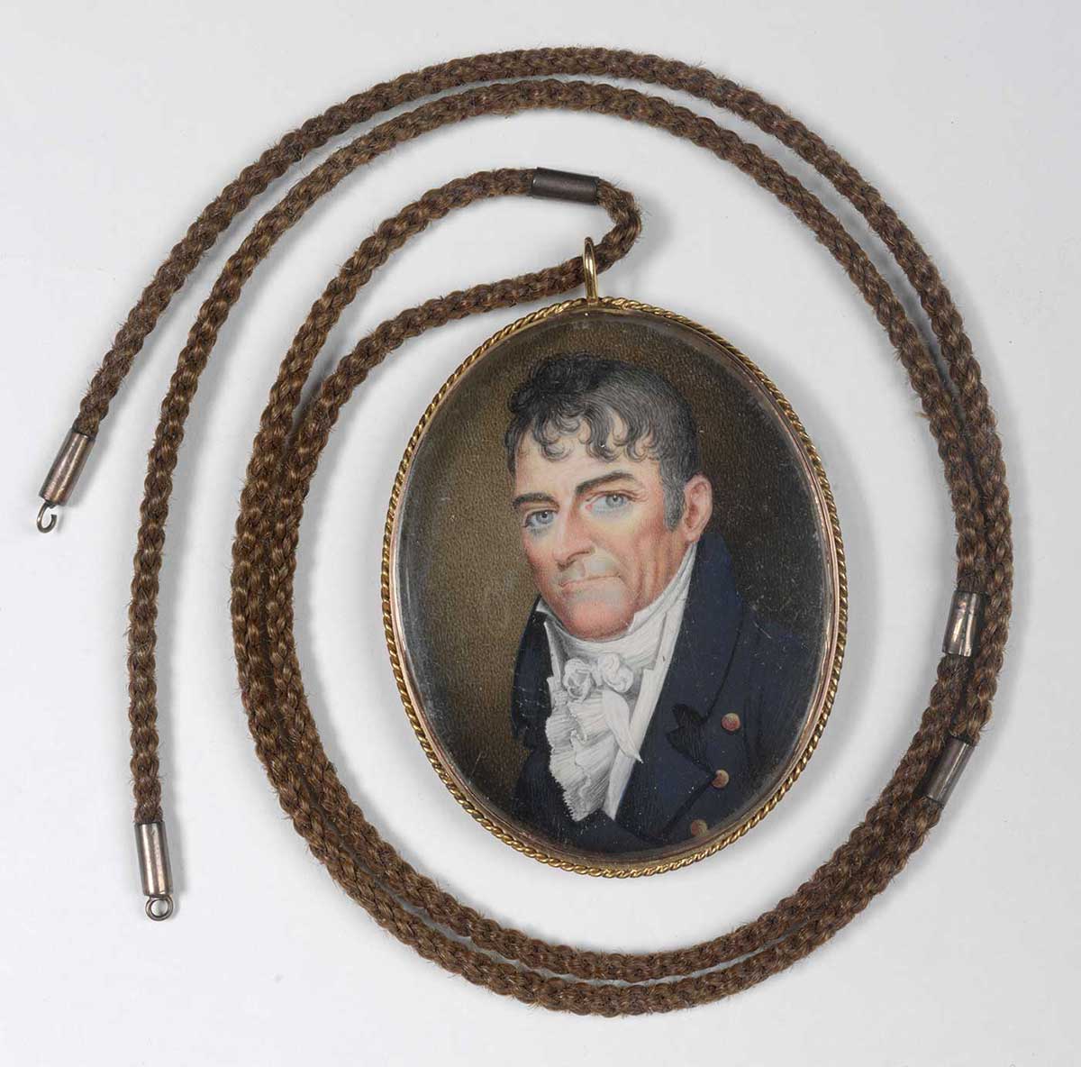 Miniature portrait with necklace attached. The portrait depicts a man wearing a blue coat and a flouncy cravat. He has blue eyes and black wavy hair. - click to view larger image