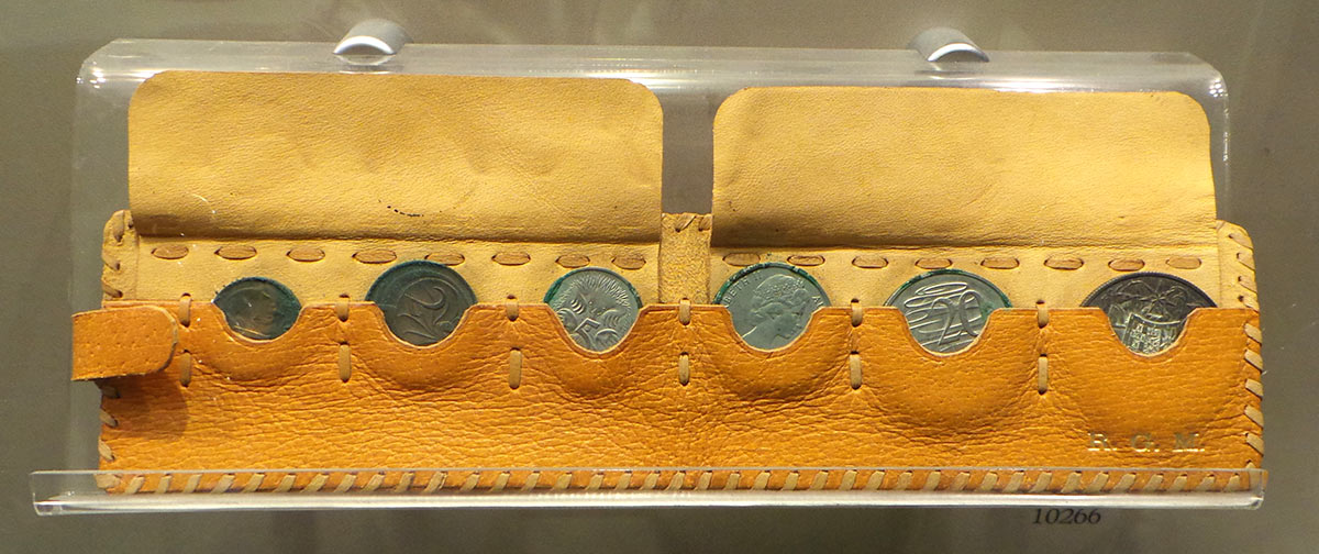 A yellow leather pouch containing six tarnished coins – the one, two, five, 10, 20 and 50-cent pieces. The initials R G M are embossed in gold.
