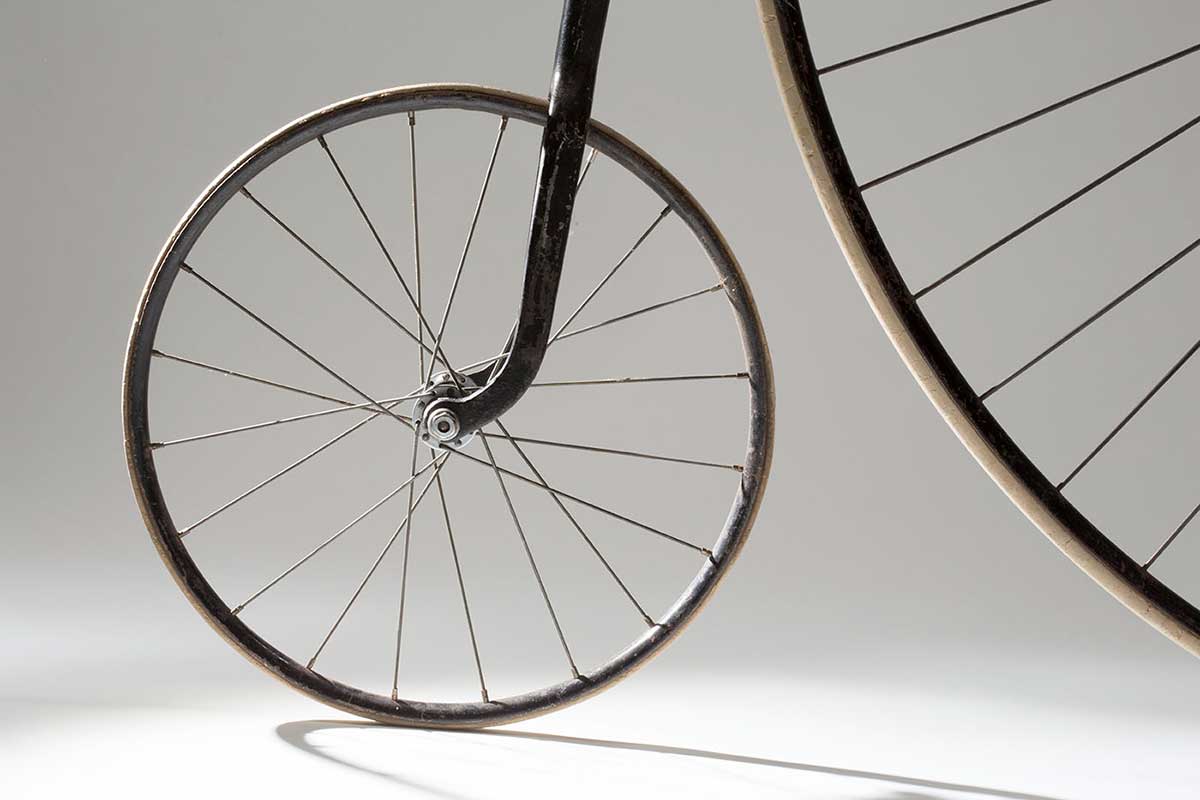 Close up image showing the smaller rear wheel and part of the front wheel of a penny-farthing bicycle. - click to view larger image
