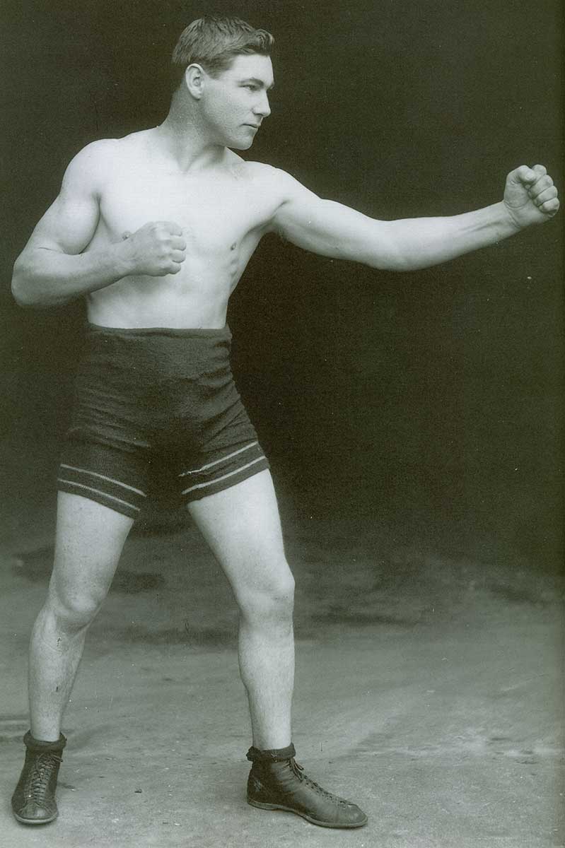 Side view of Les Darcy in shorts and boots. His fists are closed and he is leading with the left. - click to view larger image