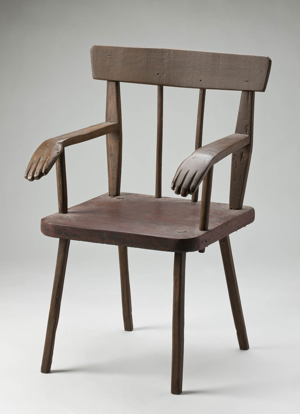 A wooden chair with decorative carved hands at the end of each arm. - click to view larger image