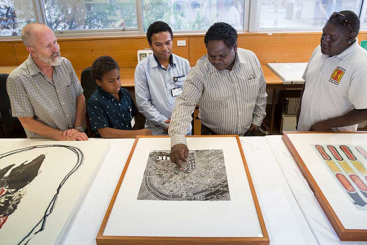 Four men and a child looking at a print on a table