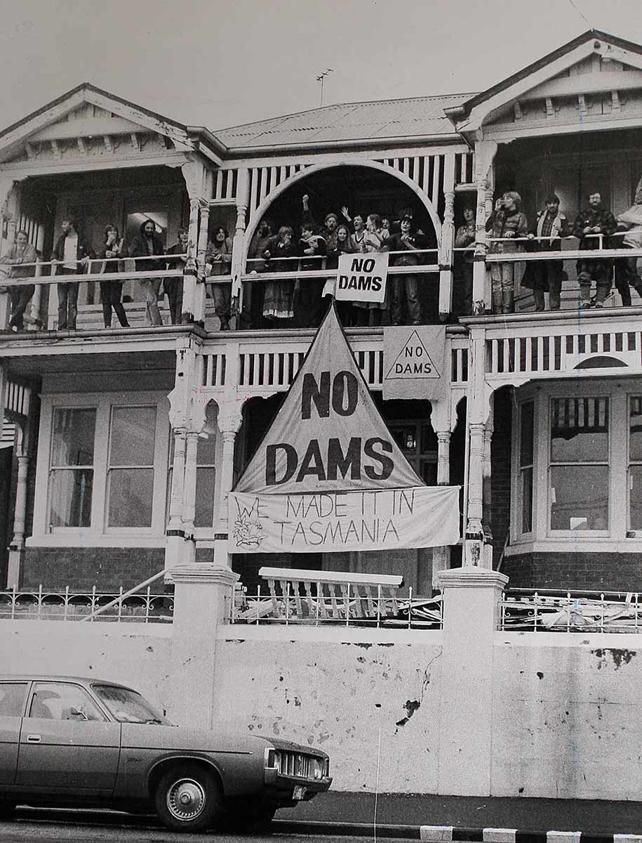 People standing on a balcony. There is a large banner with the text 