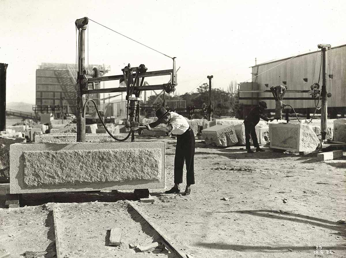 Black and white photograph of two men working on large granite blocks. - click to view larger image