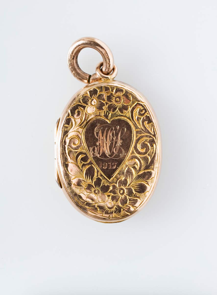 Image of the mourning locket, front view (inscribed with WOS, 1917), featuring an intricate floral design. - click to view larger image