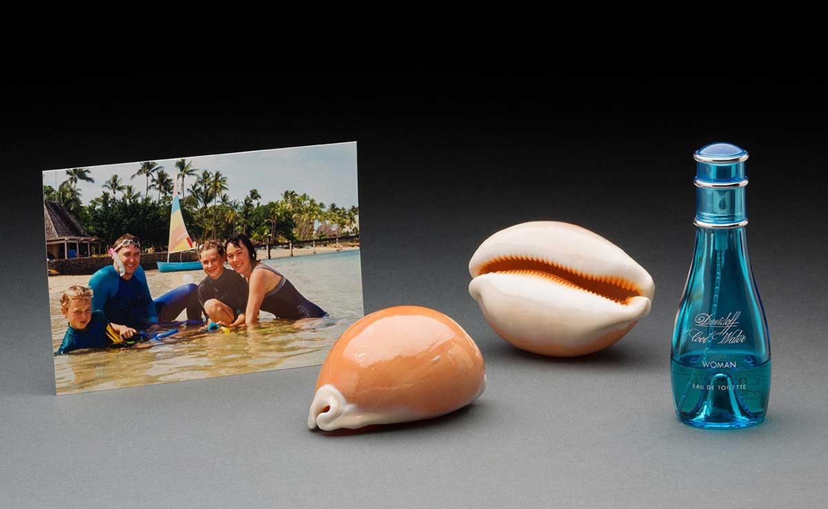 A photo of a man, woman and two boys in shallow water; two shells and a blue perfume bottle.