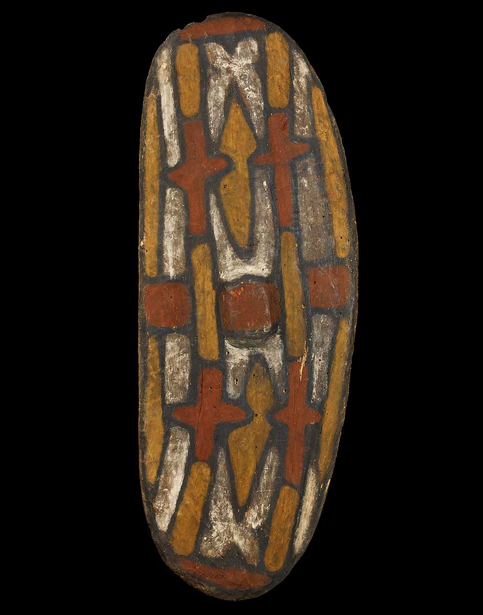 Oval shaped wooden shield with painted design in red, yellow, white and black. - click to view larger image