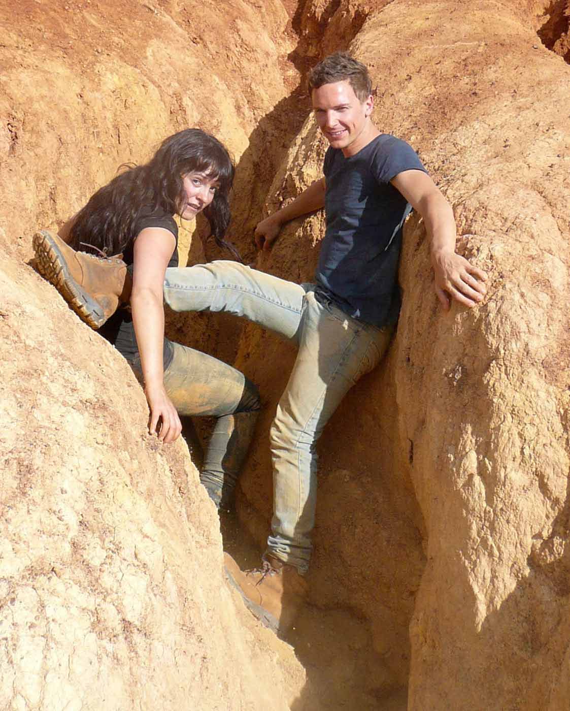 A woman and man support themselves in a rock crevice while posing for the camera. - click to view larger image