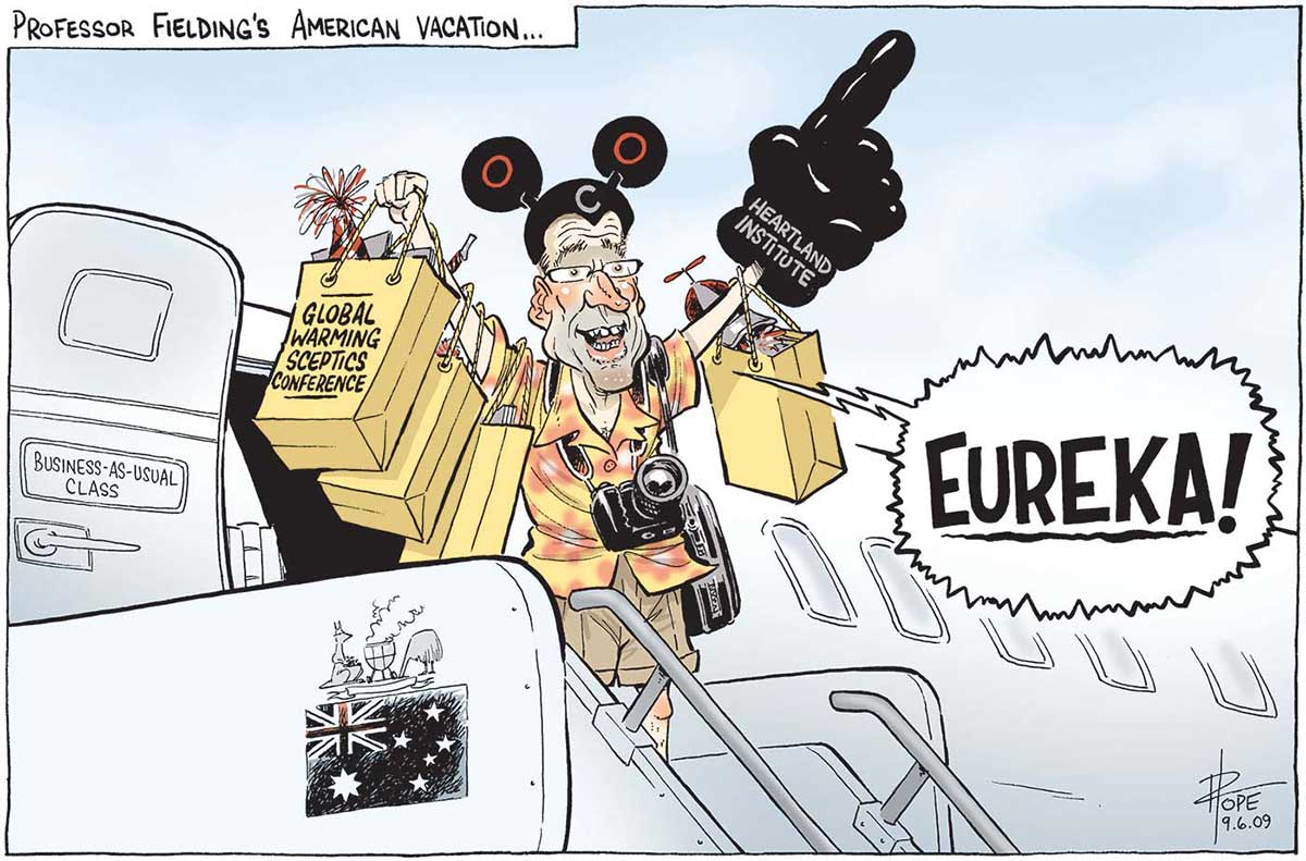 A colour cartoon titled 'Professor Fielding's American vacation ...'. Steve Fielding emerges from an aeroplane and stands at the top of the stairway, dressed as a tourist. He shouts 'Eureka!', carries 'Global Warming Sceptics Conference' showbags and wears Mickey Mouse style ears and an oversized 'Heartland Institute' foam hand. The plane door is labelled 'Business-as-usual' class and the Australian flag and coat of arms appears on the side of the stairs. The coat of arms shows the kangaroo standing beside a smoking kettle barbecue, its pouch full of what looks like coal, while the emu buries its head. - click to view larger image