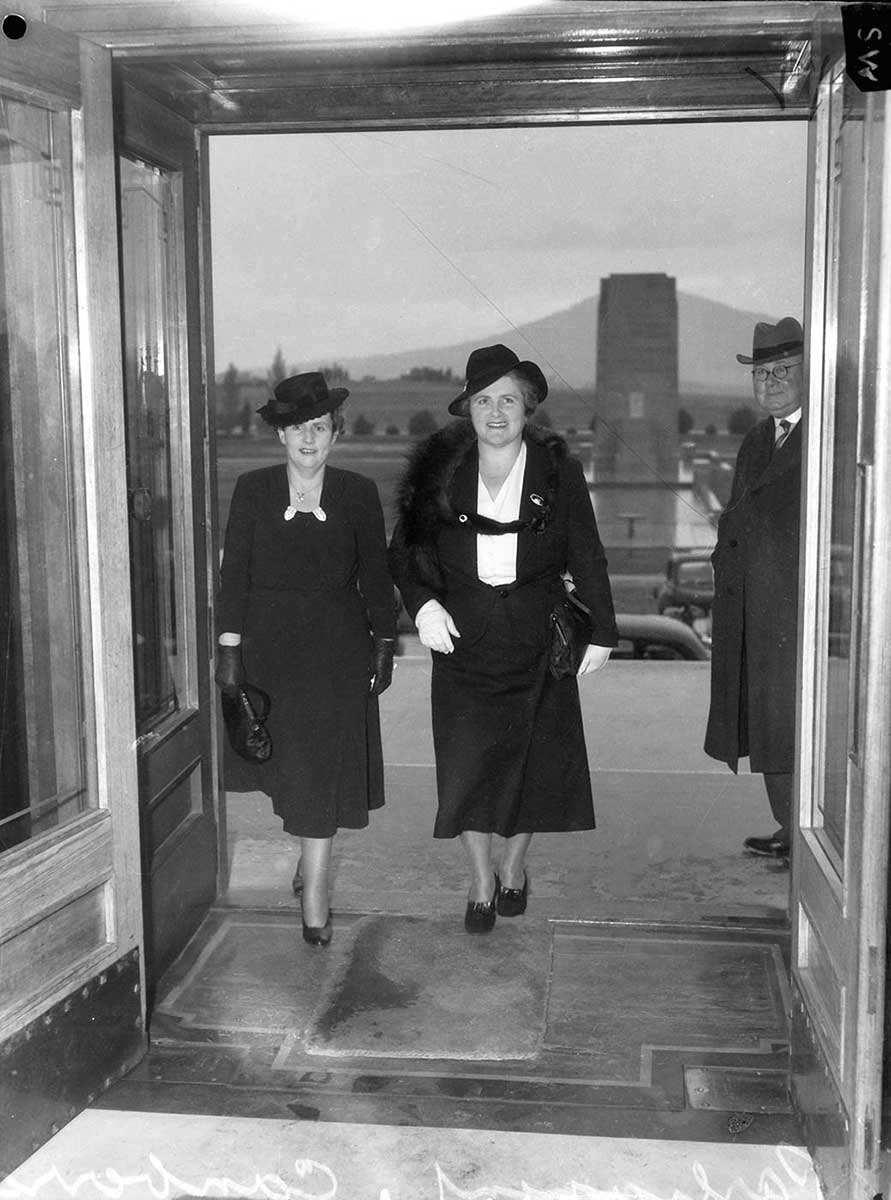 Black and white photo of Dorothy Tangney and Enid Lyons walking through the doors of Parliament House in Canberra. - click to view larger image