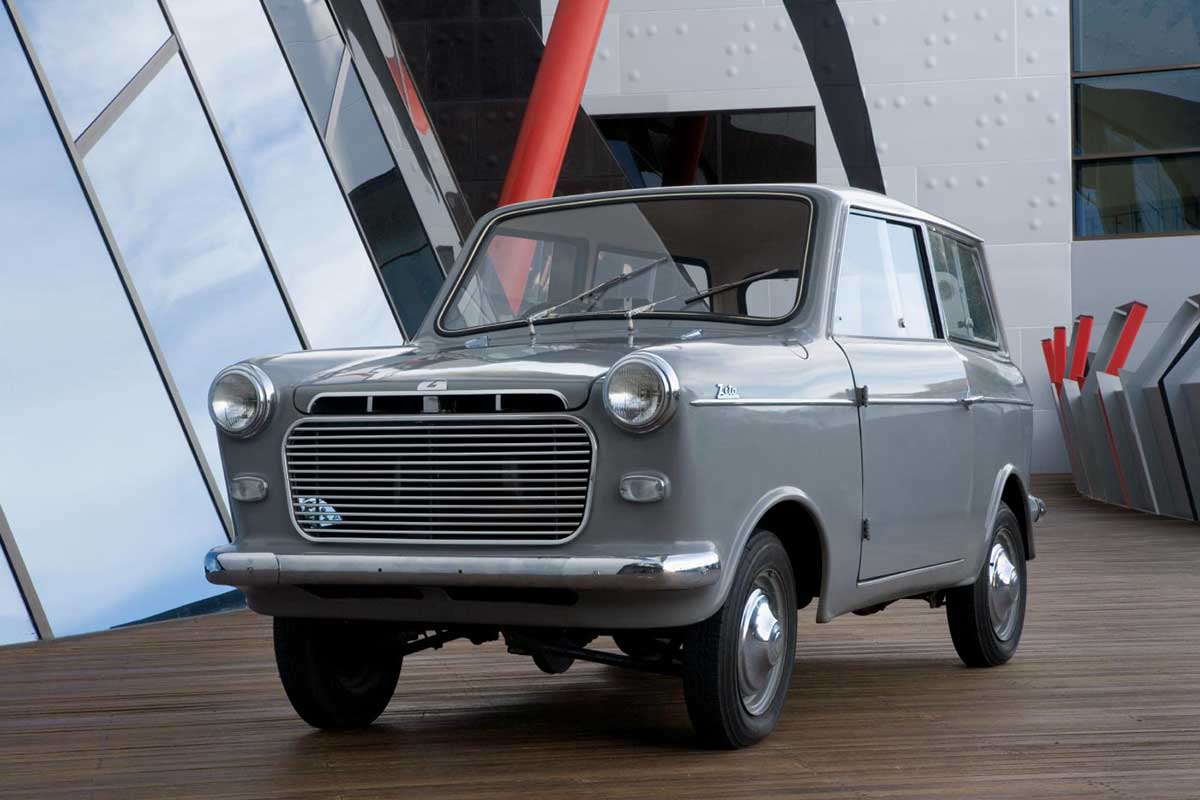 A small grey car parked on a wooden deck against an expansive pane of glass. - click to view larger image