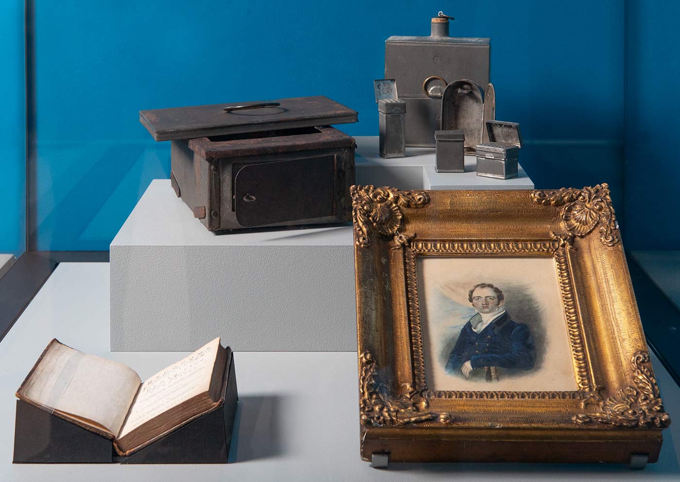 A group of eight metal components for Banks' travelling stove used on the Endeavour along with a framed portrait of Midshipman William Harvey and two loose/detached parts.