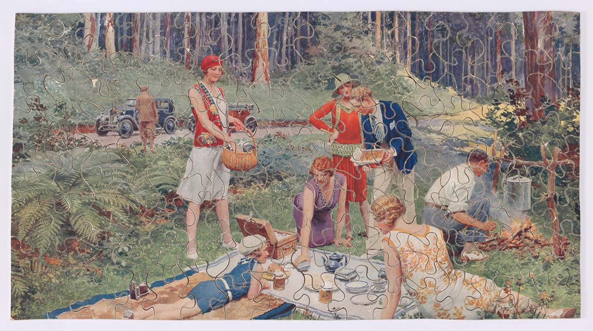 Jigsaw puzzle depicting a family having a picnic in a forest. Two cars can be seen in the background. - click to view larger image