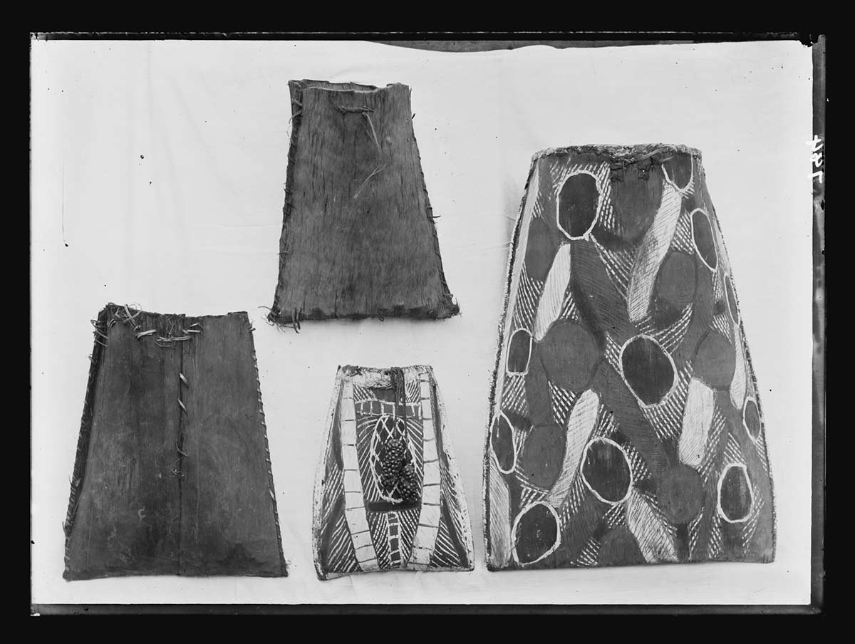 Four bark containers collected by Basedow on Bathurst Island, Northern Territory 1911. The largest container is on the right side of the image. Two of the smaller containers have plain sides. The other small container and the large container have customary Aboriginal markings and designs on them in the form of stripes, bands and oval shapes. - click to view larger image