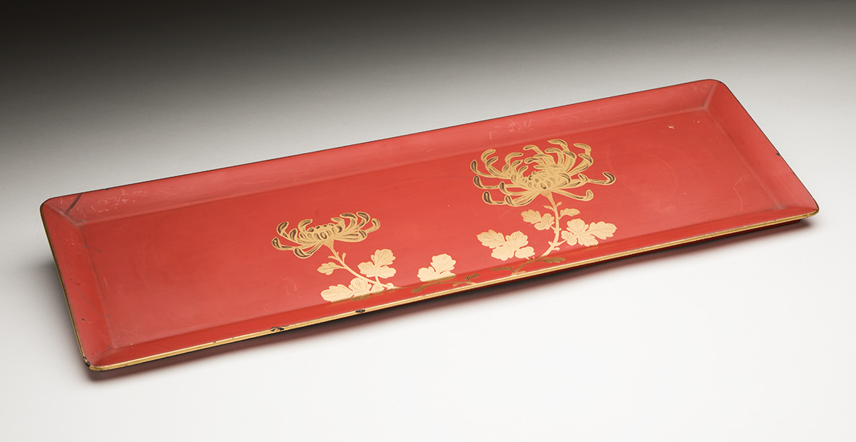 A small red lacquered tray with floral decoration.